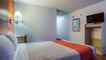 A hotel room with a bed, a desk, a TV, and a wardrobe.