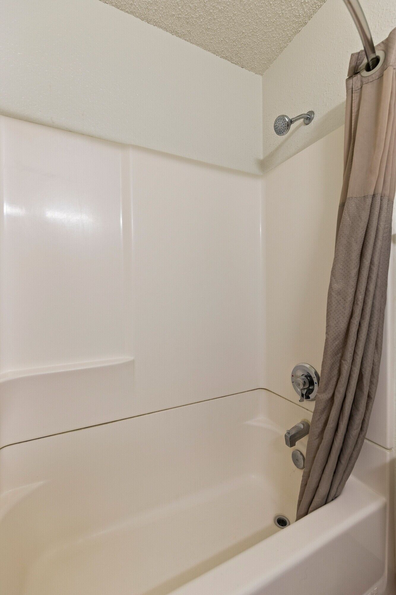 A white bathtub with a showerhead and curtain.