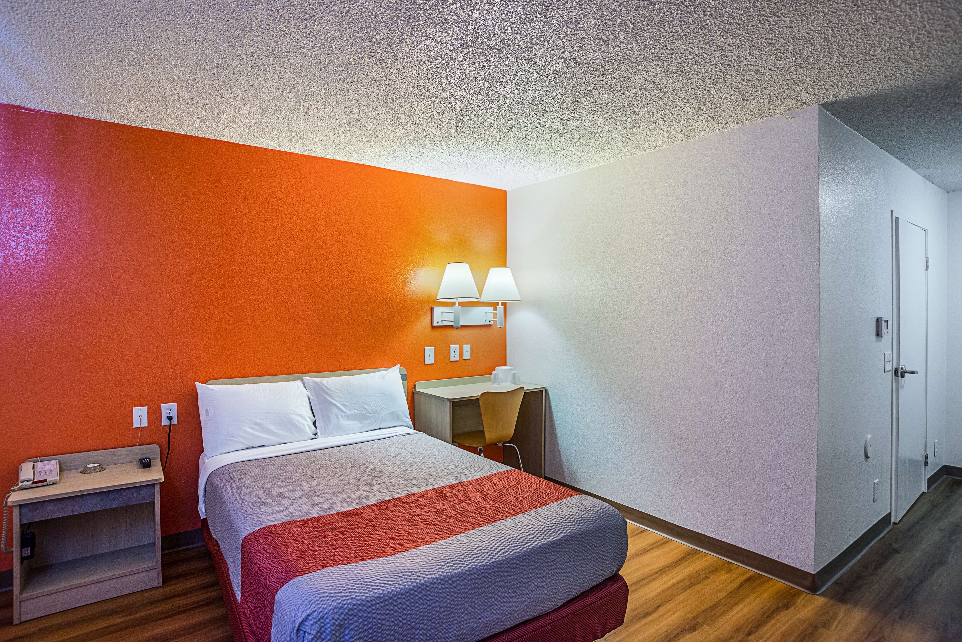 Une chambre d’hôtel équipée d’un lit, d’une table de chevet, d’un bureau et d’une lampe.