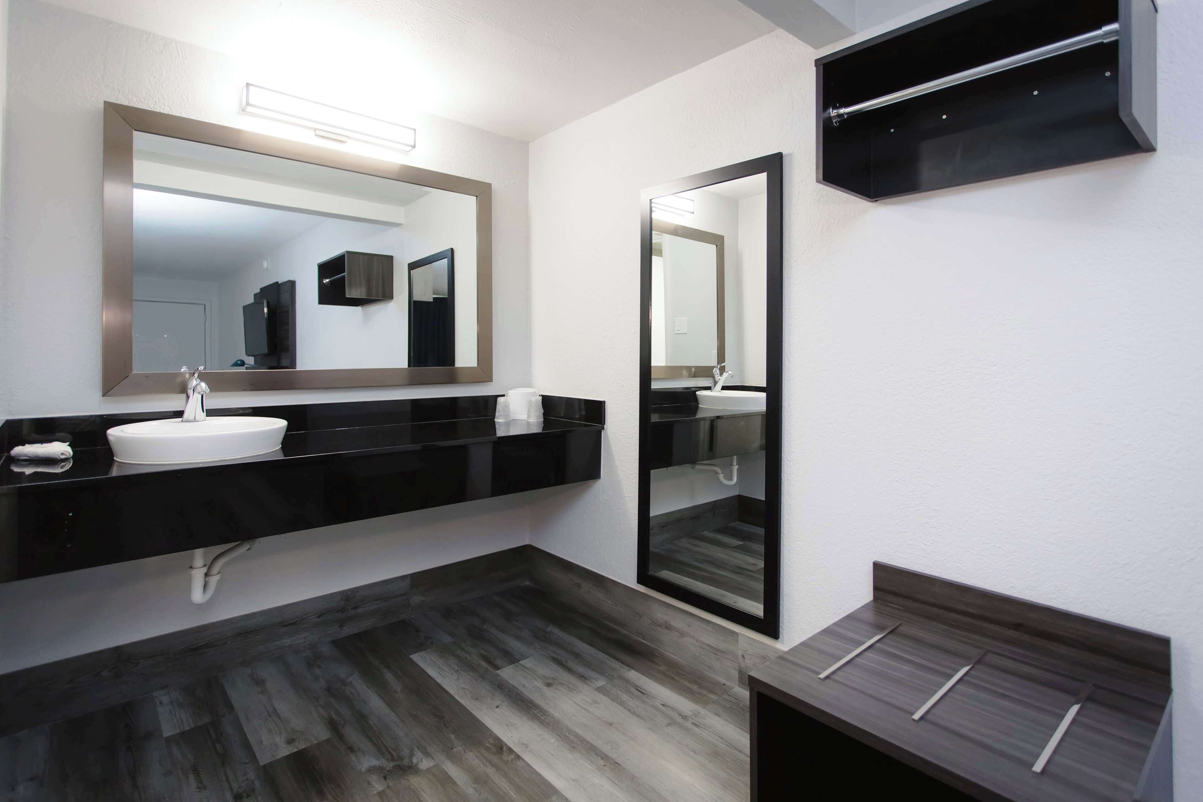 A modern bathroom with a black vanity, white sink, and a large mirror.