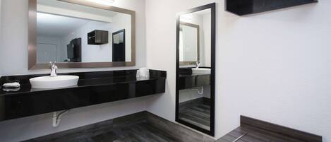 A modern bathroom with a black vanity, white sink, and a large mirror.