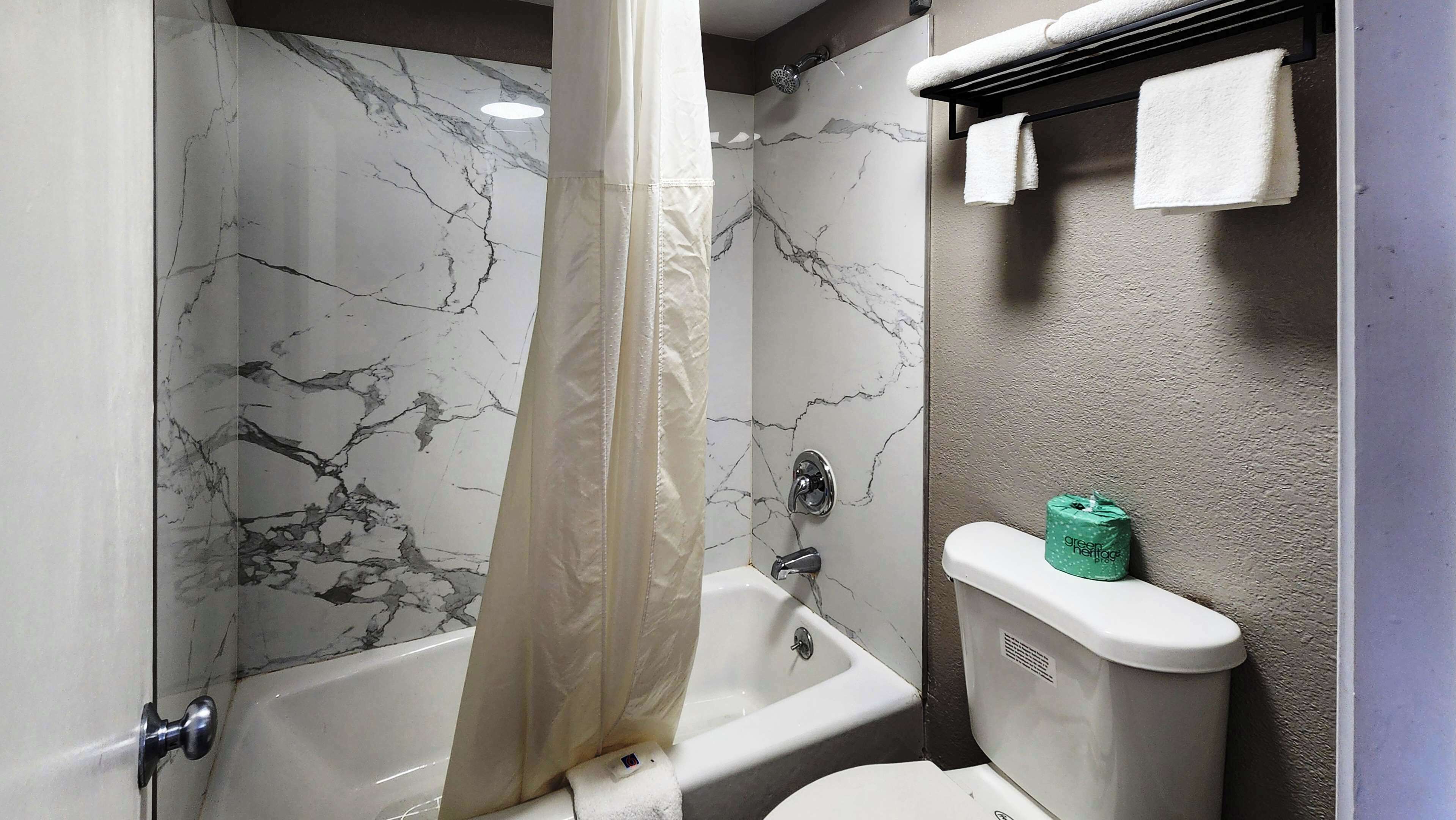 Une salle de bain avec une baignoire, des toilettes et un rideau de douche.