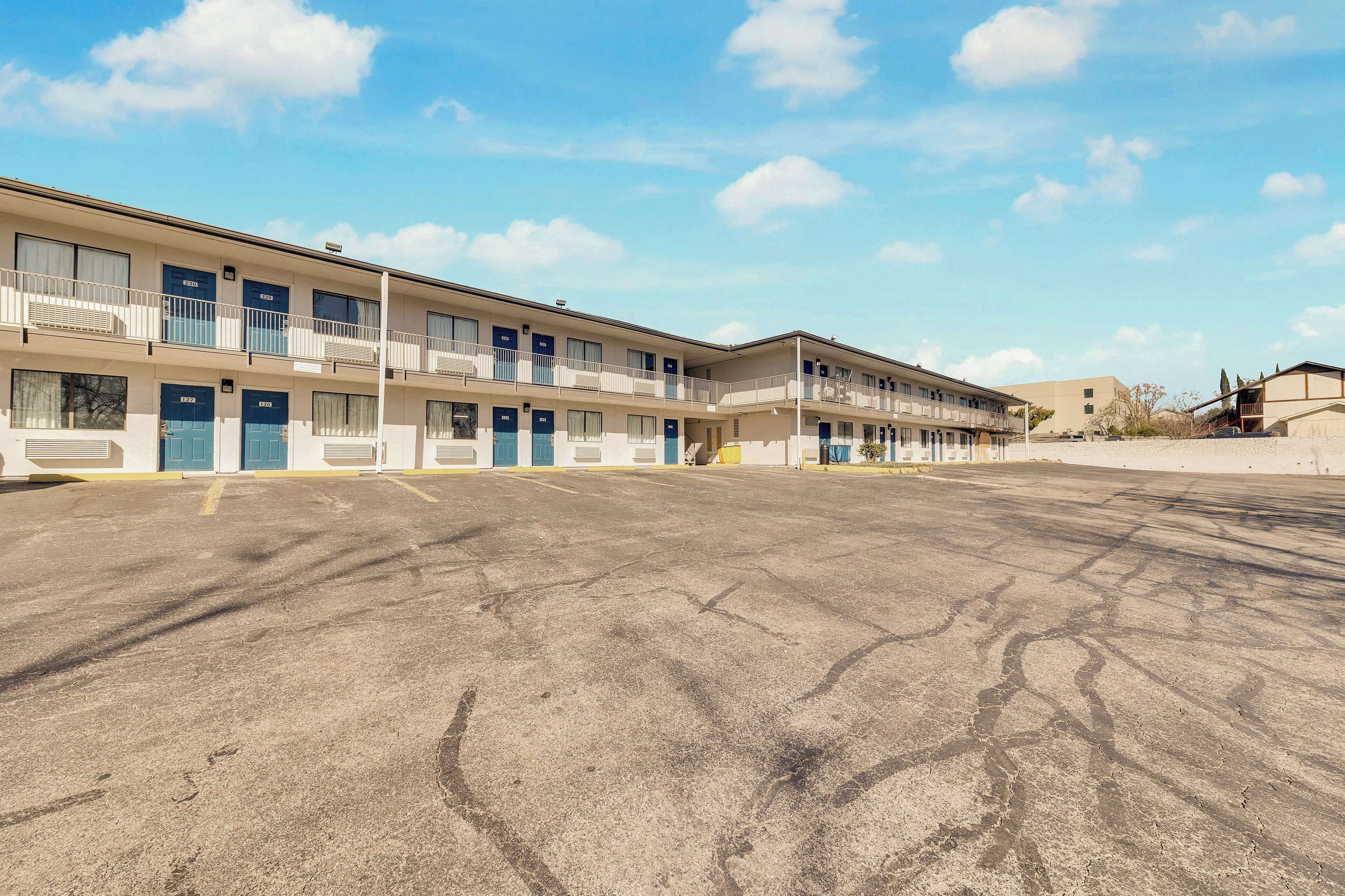 A multi-story motel with a parking lot in front.