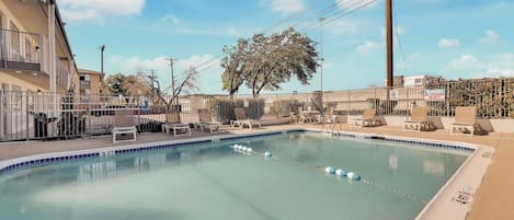 A swimming pool with lounge chairs and a fence.