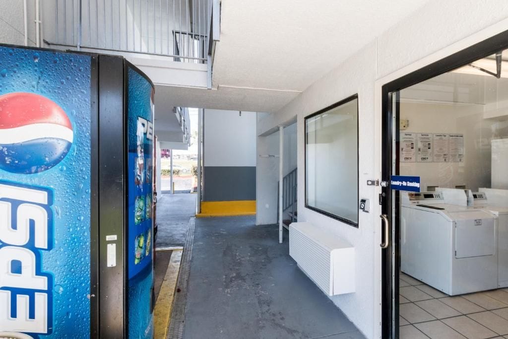 Un pasillo con una máquina expendedora, lavandería y una puerta con un letrero.