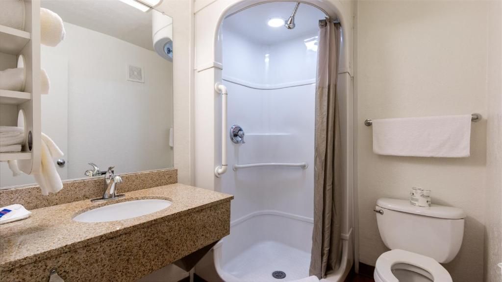 Une salle de bain avec une douche, deux lavabos, des toilettes et un porte-serviettes.