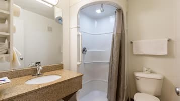 A bathroom with a sink, mirror, shower, and toilet.