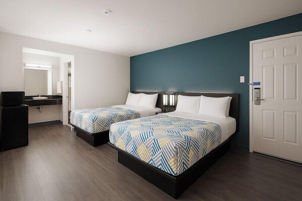A hotel room with two beds, a small desk, a mirror, and a door. - Motel 6 Westminster, CA - North (Westminster)