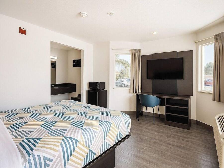 Een hotelkamer met een bed, een bureau, een stoel, een televisie en een raam.