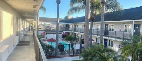 Un hotel con zona de piscina, varios balcones y palmeras.