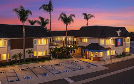 A hotel with a parking lot, including handicapped spaces, and a sign indicating the number 6.