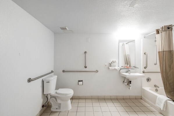 A standard bathroom with a toilet, sink, and bathtub. It includes grab bars and a shower curtain. - OYO Hotel Houston Katy Freeway (Houston)