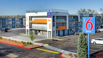 Un motel con estacionamiento, señalado con un cartel con el número 6, y un edificio de varios pisos y balcones.