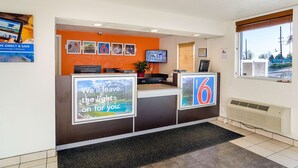 A reception area with a counter, a television, and a window with blinds.