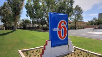 Een motelbord met het nummer 6, omgeven door een verzorgd gazon en bomen.