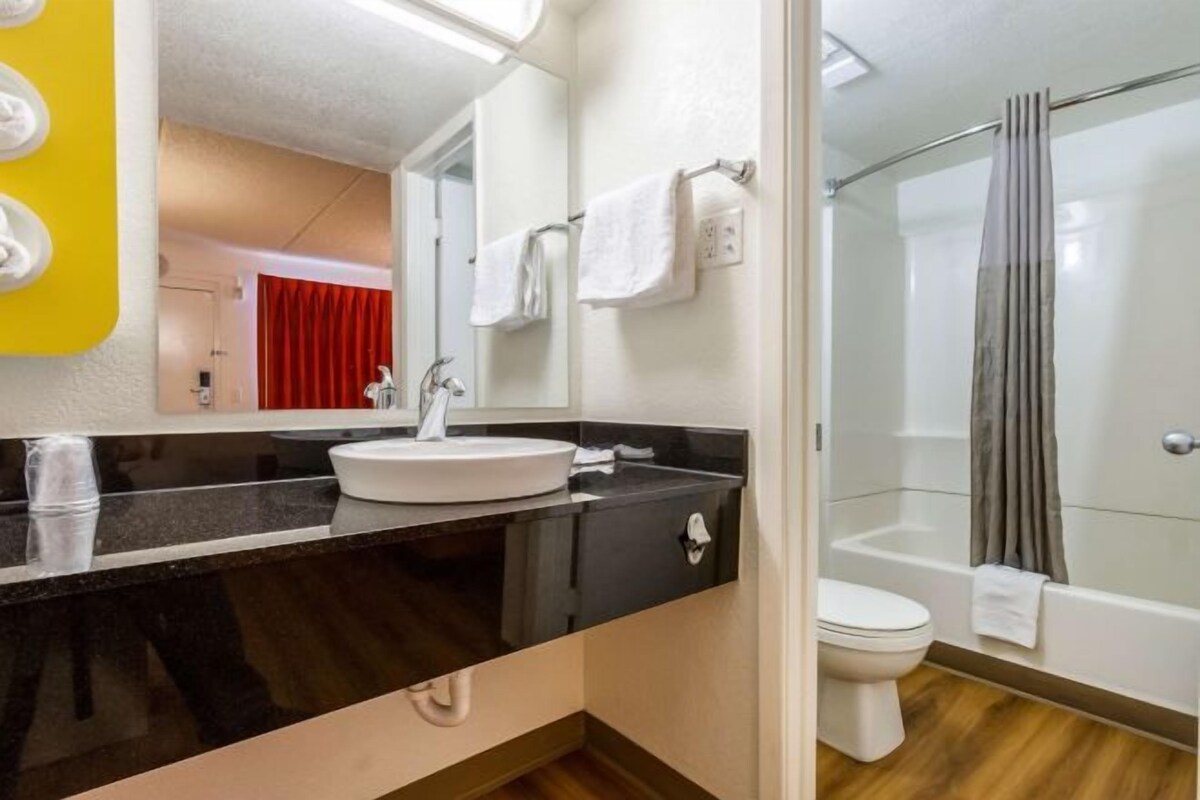 A bathroom with a black countertop, white sink, and a glass shower enclosure.