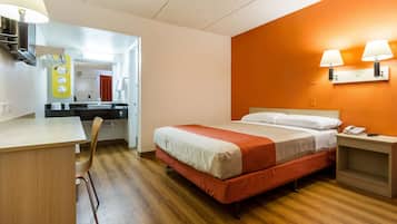 Hotellihuone, jossa on sänky, työpöytä, tuoli, peili ja kylpyhuone, joka näkyy avoimen oven läpi.