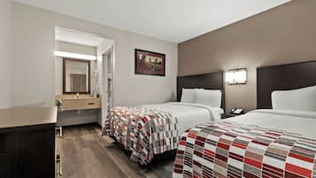 Una habitación de hotel con dos camas, un baño y un pasillo.