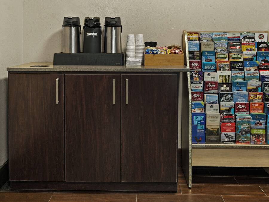 Un mueble de madera con dos cajones y una encimera con termos y una caja de pañuelos.