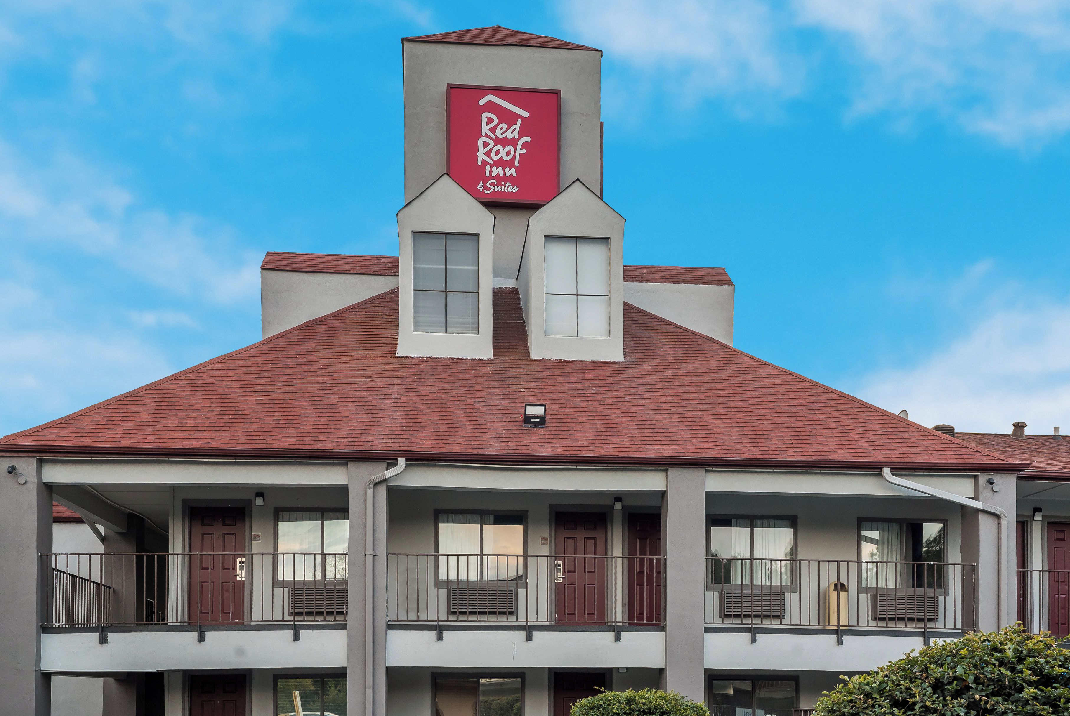 A two-story building with a red roof and a sign for Red Roof Inn & Suites.