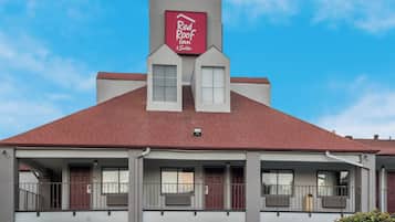 A two-story building with a red roof and a sign for Red Roof Inn & Suites.