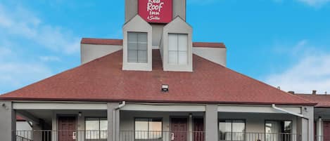 A two-story building with a red roof and a sign for Red Roof Inn & Suites.
