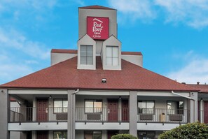 Un edificio de dos pisos con techo rojo y un letrero de Red Roof Inn & Suites.