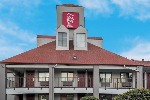A two-story building with a red roof and a sign for Red Roof Inn & Suites.