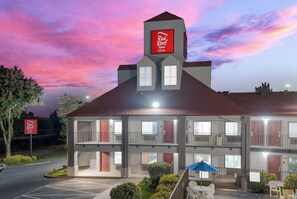 A two-story Red Roof Inn with a flat roof, multiple windows, and a sign indicating it offers suites.
