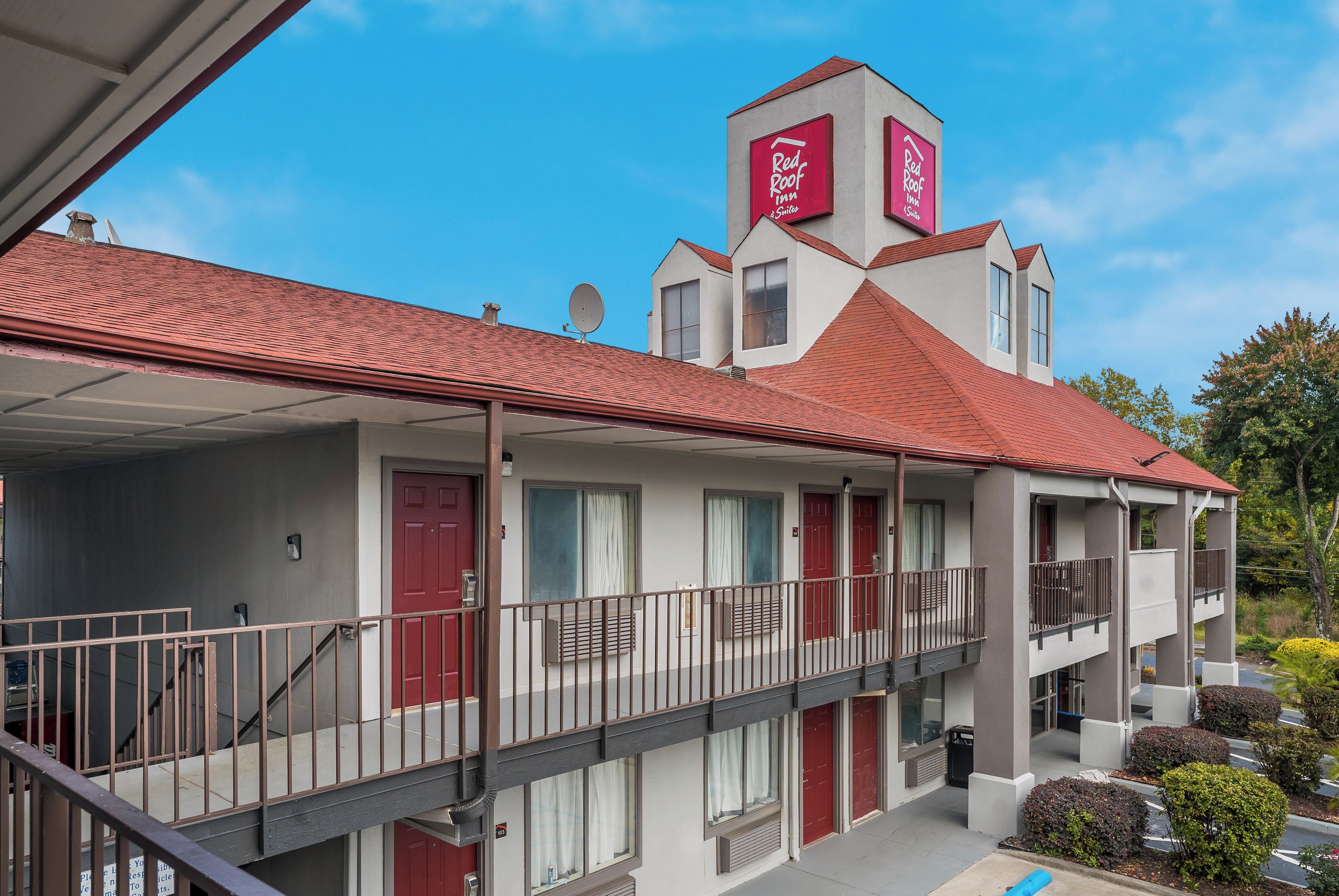Un motel de dos pisos con techo rojo, varios balcones y un cartel que indica que es un Red Roof Inn & Suites.