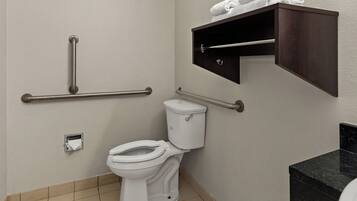 A bathroom with a toilet, grab bars, a towel rack, and a toilet paper holder.