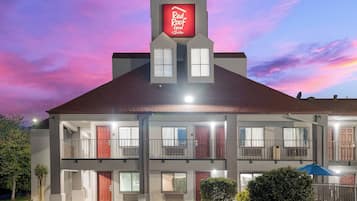 Un hotel con un letrero rojo que dice 'Red Roof Inn & Suites' y una estructura de dos pisos con varias ventanas y balcones.