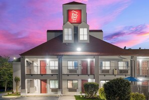 A hotel with a red sign reading 'Red Roof Inn & Suites' and a two-story structure with multiple windows and balconies. - Red Roof Inn Spartanburg - I-85 (Spartanburg)