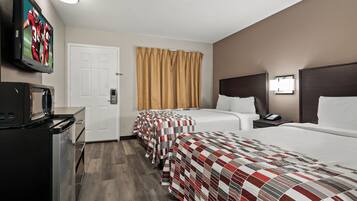 A hotel room with two beds, a TV, a desk, and a bathroom door.