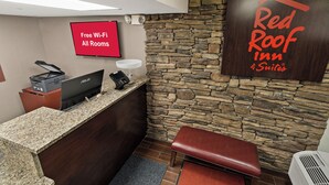 A reception area with a stone wall, a Red Roof Inn sign, a desk with a computer, a printer, and a cash register. - Red Roof Inn Spartanburg - I-85 (Spartanburg)