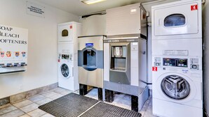 A laundry facility with multiple washing machines, a drying machine, and a sign indicating the motel is not responsible for unattended items. - Motel 6 Linthicum Heights, MD - BWI Airport (Linthicum Heights)