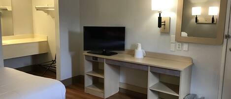 Ein Hotelzimmer mit zwei Betten, einem Schreibtisch, einem Fernseher, einem Spiegel und einem Mülleimer.