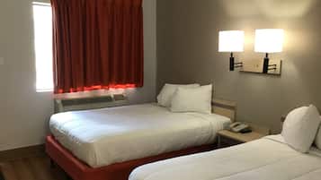 A hotel room with two beds, a window with red curtains, an air conditioning unit, and two wall-mounted lamps.