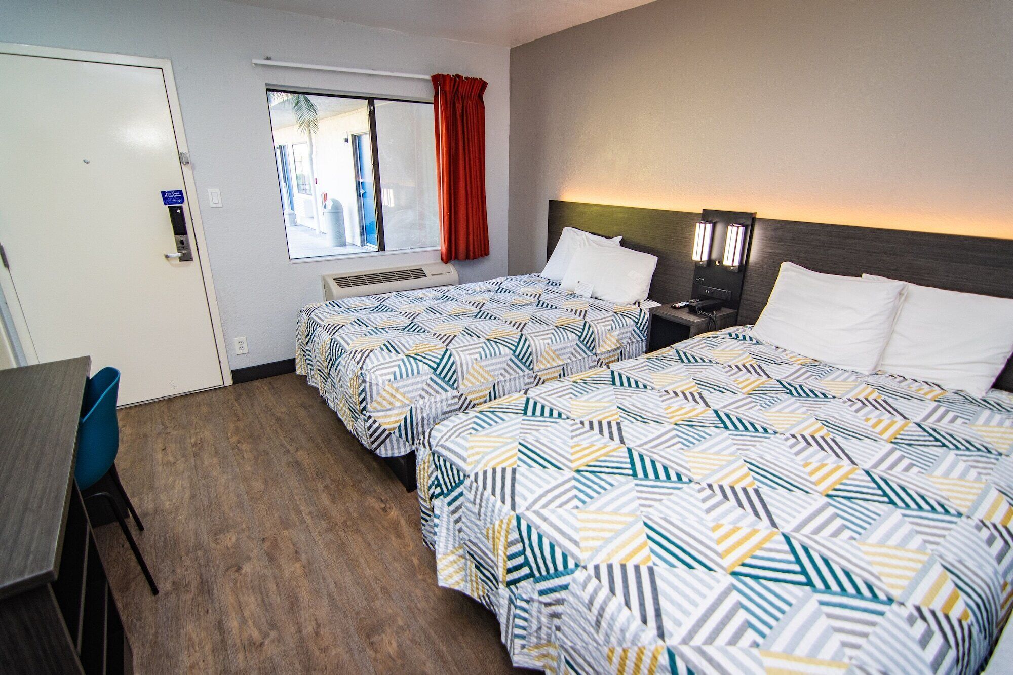 Een hotelkamer met twee bedden, een bureau en een raam met uitzicht.