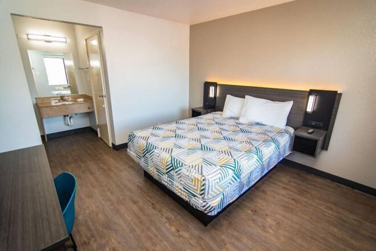 Une chambre à coucher avec un lit, des tables de chevet, un miroir et un petit bureau.