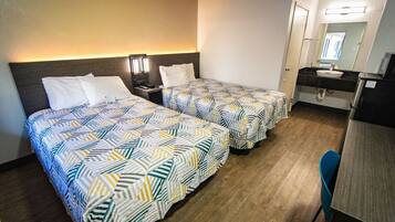 Une chambre d’hôtel avec deux lits, un bureau, une chaise, un miroir et une salle de bain.