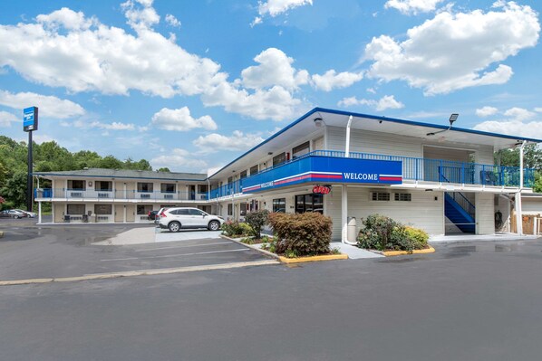 A motel with a 'Welcome' sign, a parking lot, and a clear blue sky.