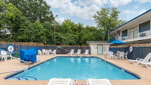 A swimming pool with lounge chairs and a small building with a blue awning. - Rodeway Inn Winston Salem Route 52 (Winston-Salem)