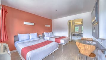 Una habitación de hotel con dos camas, una mesa de comedor y una kitchenette.