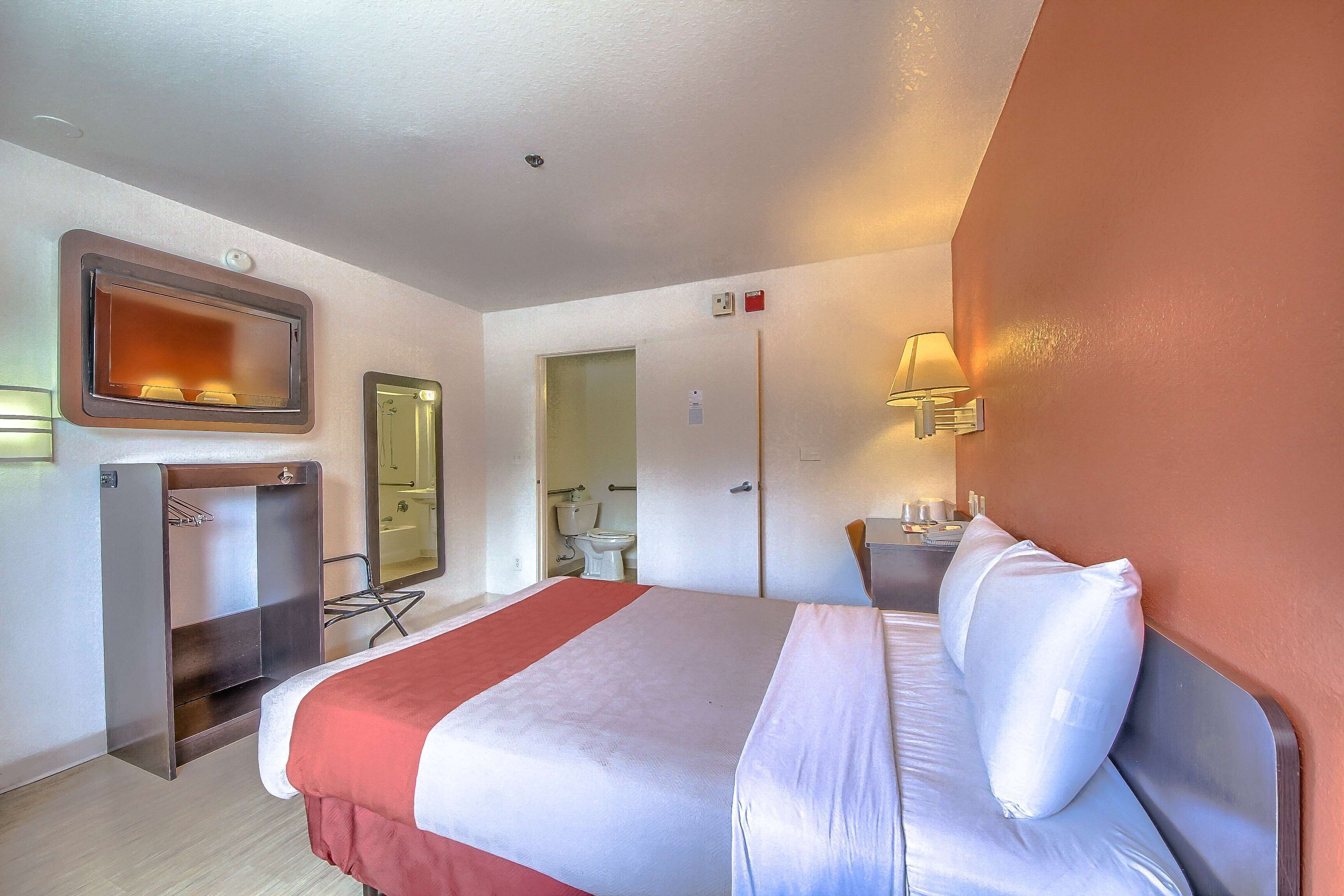 Ein Hotelzimmer mit Bett, Schreibtisch, Spiegel, Kleiderschrank und einer Badezimmertür.
