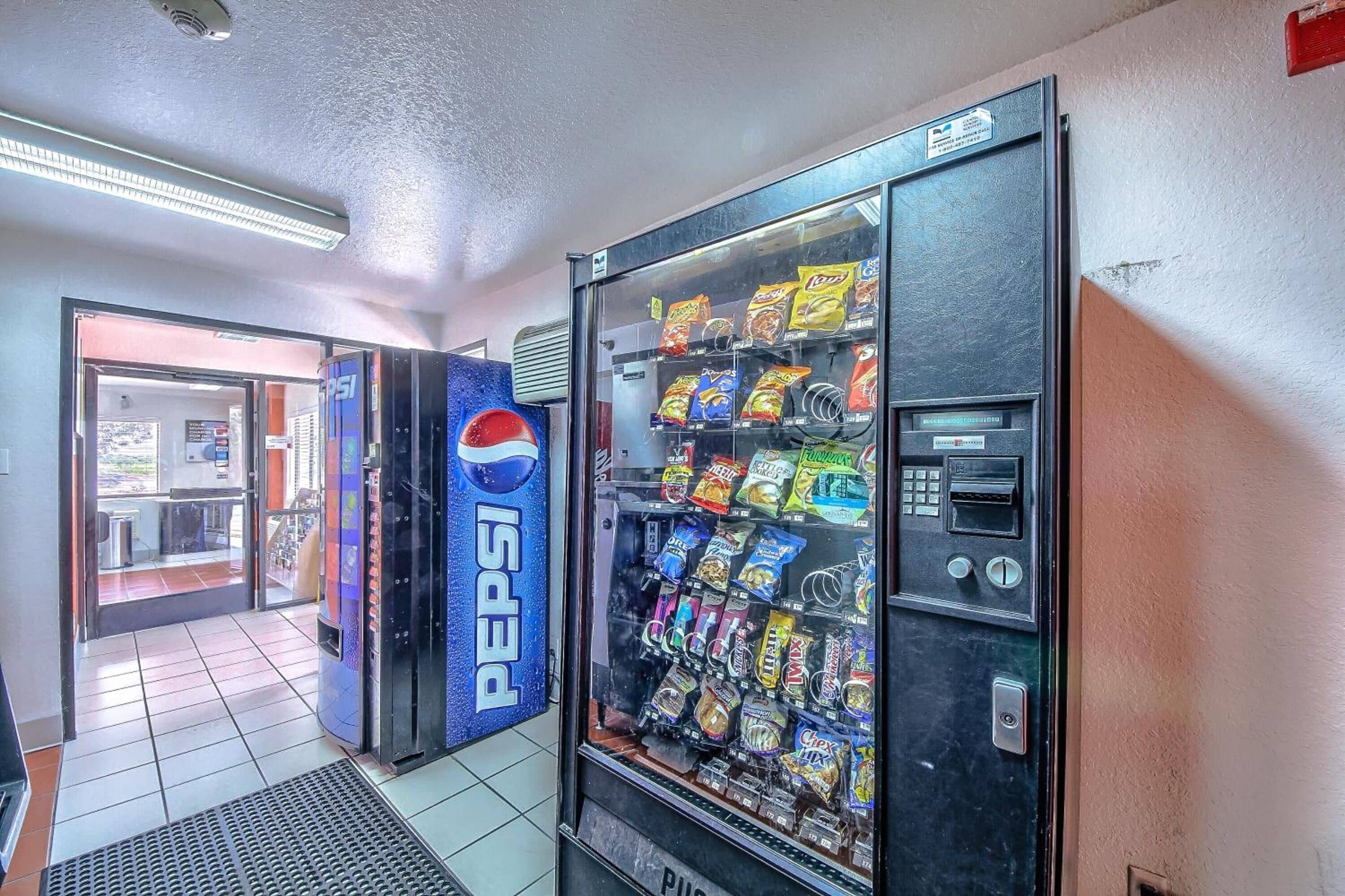 A vending machine stocked with snacks and beverages, including Pepsi, in a commercial setting.