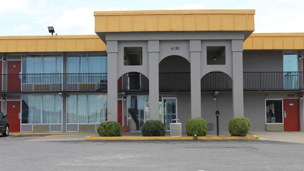 Un edificio con techo amarillo, número 5120, que presenta una entrada central con puerta de cristal y un pequeño alero.