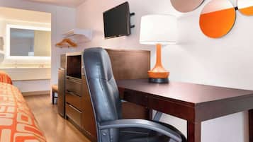 Une chambre d’hôtel avec un lit, un bureau, une chaise, une télévision et une lampe.