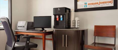 A modern office space with a desk, computer, printer, water dispenser, and a framed advertisement on the wall.