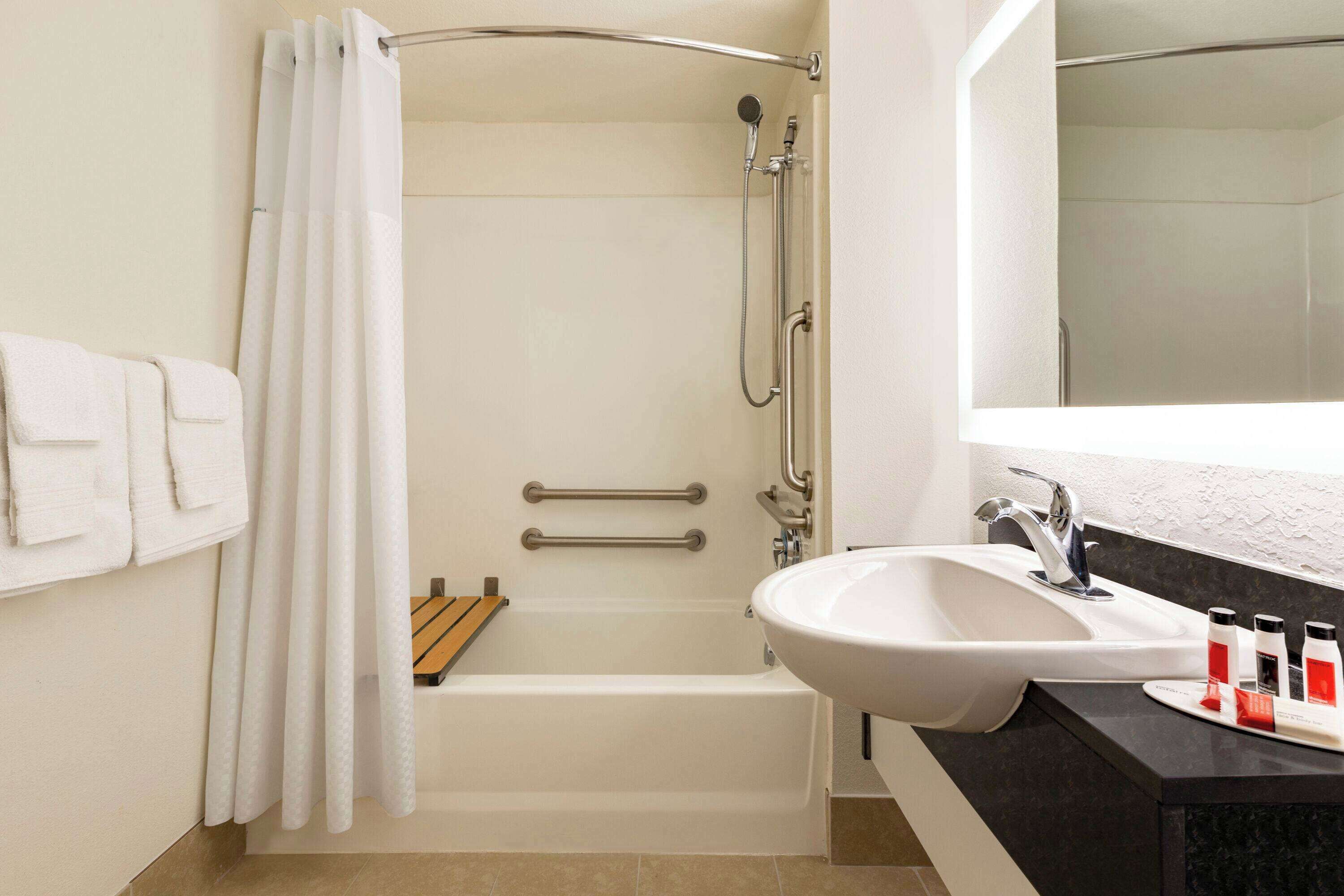 A modern bathroom with a bathtub, shower, and sink.